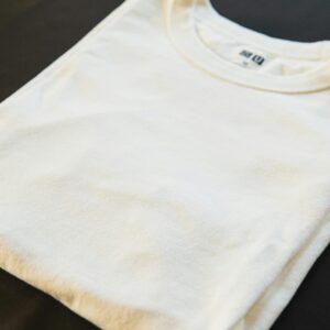 A folded white t-shirt placed on a dark surface, showcasing minimalist fashion.